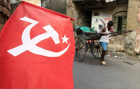 A rickshaw puller moves past a flag of the Communist Party of India (Marxist) in Kolkata.