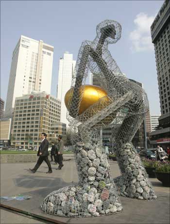 People walk past a statue titled 'Seoul broods a golden egg' at the Seoul city hall plaza in central Seoul, South Korea.