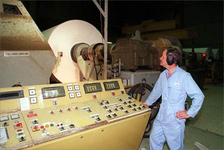 A technician checks a paper machine.