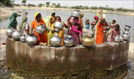 Women gather at a village well to draw drinking water.