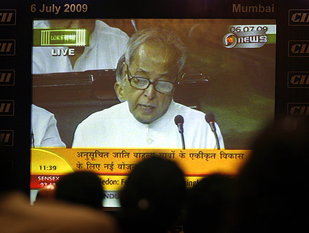 Indian journalists and businessmen watch as Finance Minister Pranab Mukherjee (on screen) presents the annual budget.