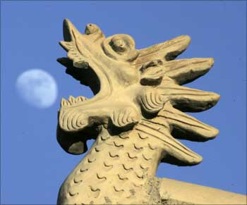 Chinese architecture style dragon head is seen as the moon rises at Jiayuguan Pass, China