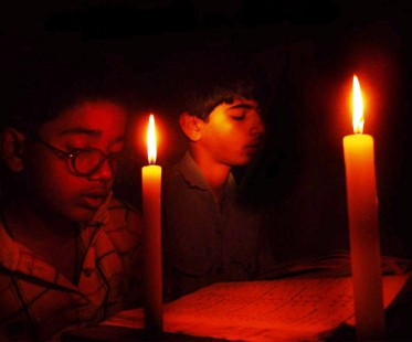 Indian boys study in candle-light because of a power cut-off in Bhopal.