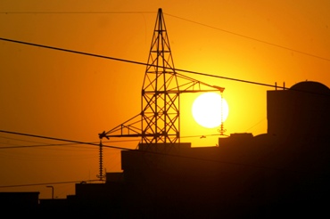 Sun sets behind a power tower near a building in New Delhi.